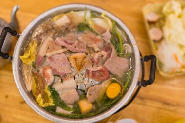 Tayland usulü ızgara alüminyum tavada pişmiş domuz eti ve kaynar çorba. Thai 'nin adı Moo Krata, ahşap masada barbekü partisi..