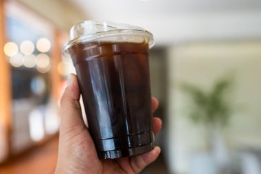 Elinde buzlu sade kahve ya da plastik bardakta americano kahvesi.,