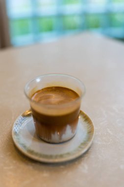Ahşap bir masanın üzerindeki kirli kahve. Üstünde sağlam bir espresso tabakası, altında soğuk süt ya da krema var..
