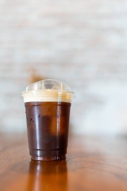 Taze doldurulmuş nitro soğuk kahve ahşap masanın üzerinde plastik bardakta.