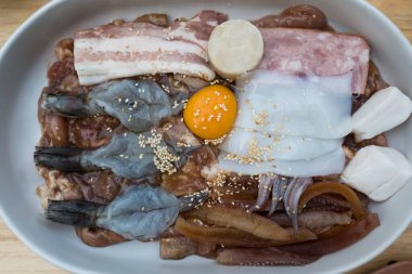 Tayland barbeküsü için hazırlanmış taze marine edilmiş et, deniz ürünleri ve yumurta sarısı. Seyircileri tadını çıkarmaya davet et, mutfak projeleri için mükemmel..