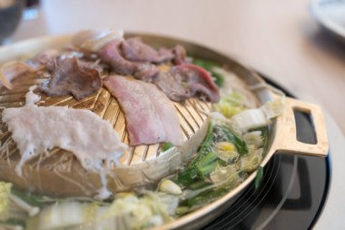 Tayland usulü ızgara alüminyum tavada pişmiş domuz eti ve kaynar çorba. Thai 'nin adı Moo Krata, ahşap masada barbekü partisi.