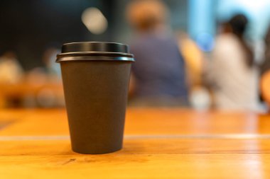 Ahşap masada siyah bir kağıt bardak.