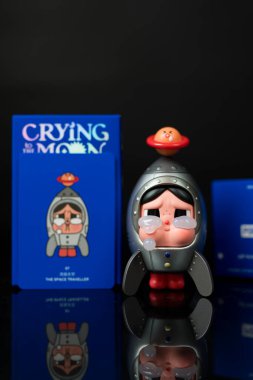 Bangkok, Tayland - 22 Aralık 2025: Mızmız bir bebeğin Uzay Gezgini Pop Mart mağazasından ay dizisi figürlerine ağlıyor, sulugöz koleksiyonlar