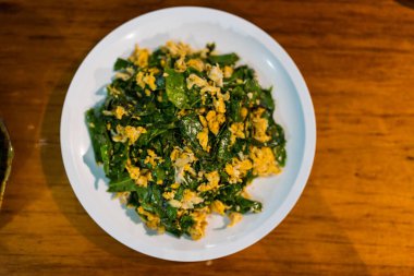 Kızarmış Malindjo yapraklarını masanın üzerinde yumurta ile karıştırır, bu menü Tayland 'ın güneyinde favoridir.