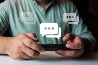 Konuşma balonunda sergilenen akıllı telefonu kullanan bir adam. Cep telefonu ekranında simge konuşma baloncukları olan metin iletileri.