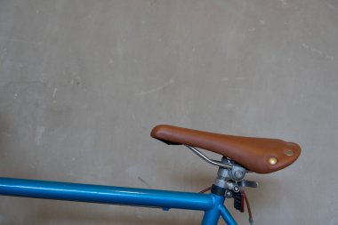 Bisiklet iskeletine monte edilmiş kahverengi deri bir bisiklet eyerinin yakın çekimi, koltuğun klasik ve rahat tasarımını vurguluyor.