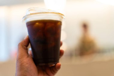 Plastik bardakta buzlu americano, çevre dostu için saman kullanmaya gerek olmayan kapaklı biberon kullanıyor. Plastik kirliliğini azaltma ve yeşil çevre dostu ürünleri destekleme kavramı.