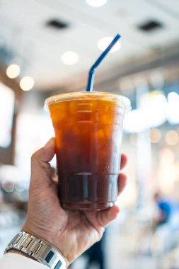 Plastik bardakta buzlu kahve tutan bir adam.