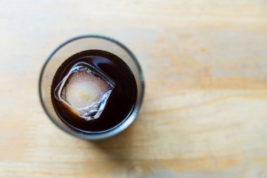 Soğuk buzlu kahve, kare buz küpleri ahşap bir masada.