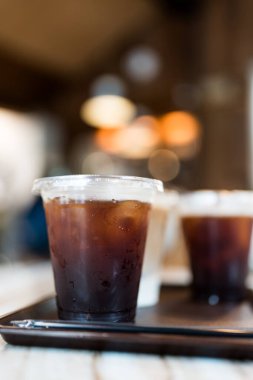 Bir bardak buzlu americano kahvesi ve ahşap tepside buz.