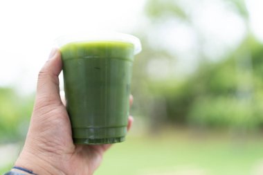 Saf buzlu kibrit içeceği, canlı yeşil renkte, arka planda bir paket bardakta..