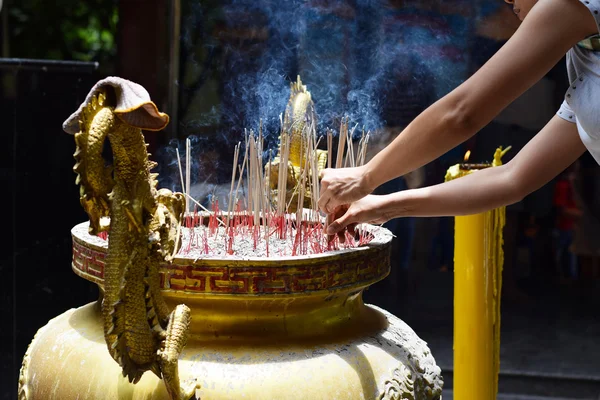 Mãos agarrando paus de incenso em um templo (fundo ) — Fotografia de Stock