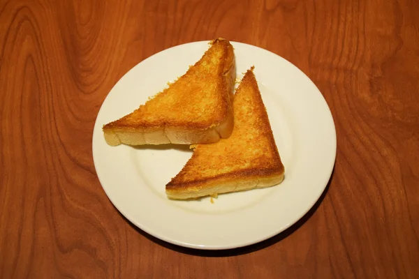 Deux morceaux de pain grillé beurré dans une assiette blanche — Photo