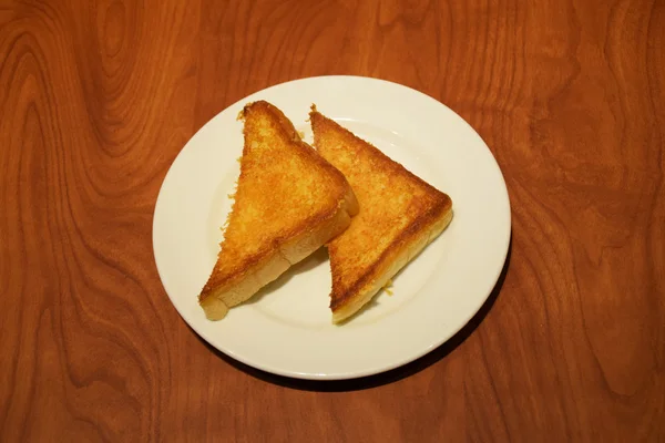Deux morceaux de pain grillé beurré dans une assiette blanche — Photo