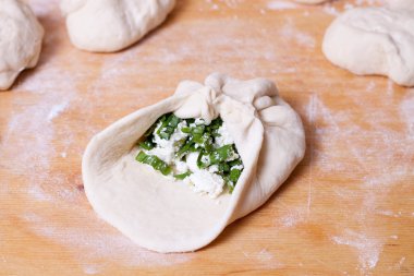 Çiğ hamur ahşap oyun tahtası üzerinde yeşil soğan dilimlenmiş