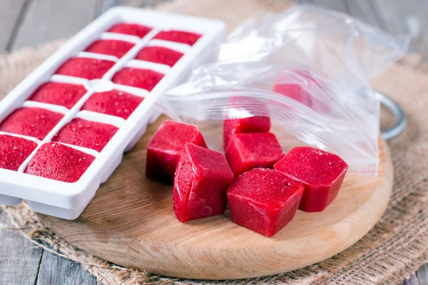 Cubos de gelo com bagas da floresta, folhas de hortelã na bandeja de cubo de gelo, na cor de fundo de madeira — Fotografia de Stock