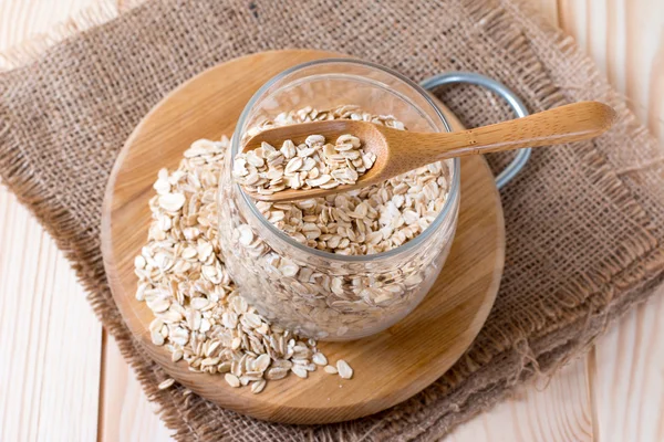 Farina d'avena cruda in vaso di vetro su fondo di legno — Foto Stock