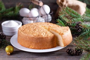 Ev yapımı yuvarlak sünger keki ya da şifon keki beyaz tabakta çok yumuşak ve lezzetli malzemelerle: yumurta, un, ahşap masa sütü. Tatil pastası ve tatlı yapmak için temel