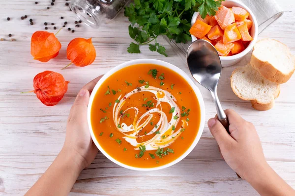 Flat-lay of kids hands and warming pumpkin cream soup with croutons on white wooden background, top view. Autumn vegetarian, vegan, healthy comfort food, eating concept — Stock Image Flat Lay Kids Hands Warming Pumpkin Cream Soup Croutons White Royalty Free Stock Photos