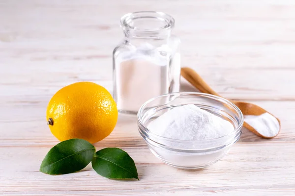 Eco-friendly natural cleaners. Vinegar, baking soda, salt and lemon on wooden table. Homemade green cleaning.