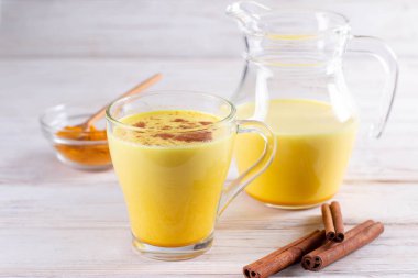 Sıcak, sağlıklı bir içecek. Zerdeçal latte, zerdeçal köklü altın süt, beyaz arka planda zencefil tozu. Ayurvedik tedavi için baharatlar. Alternatif tıp konsepti