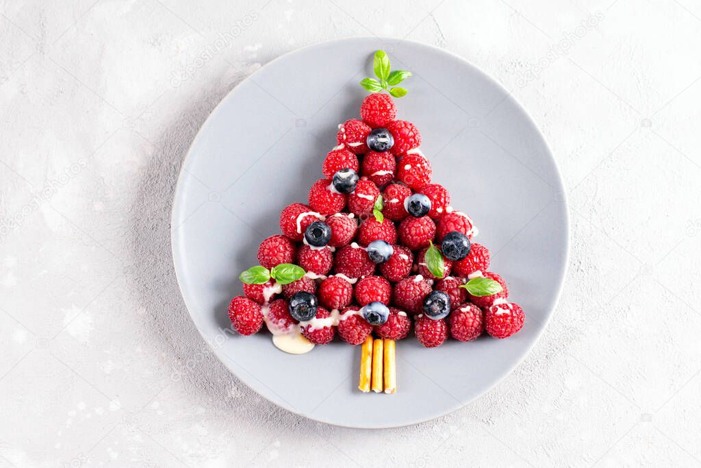 Funny christmas breakfast with christmas tree made from raspberries for child