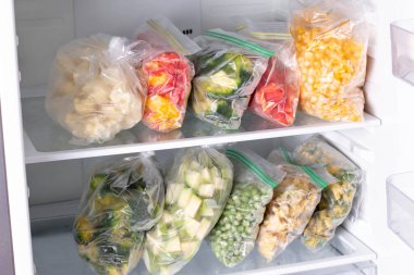 Buzdolabında farklı donmuş sebzeler olan plastik poşetler. Yatay