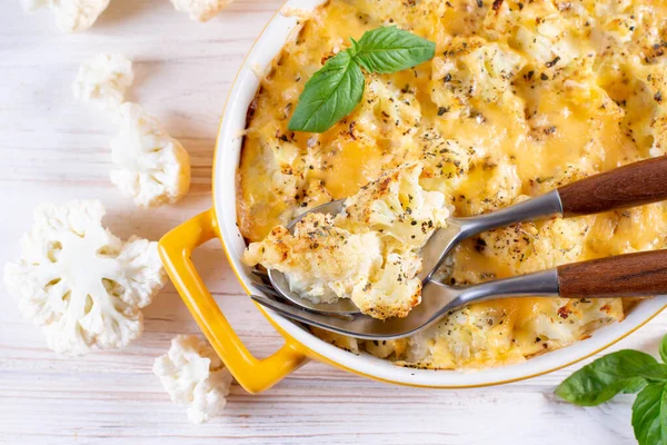 Savory food: baked cauliflower with cheese, eggs and cream in a baking dish on a table. Top view