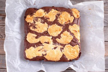 Kurabiyeli çikolatalı kek, parşömen kağıdındaki browniler, ahşap masada. Düz yatıyordu