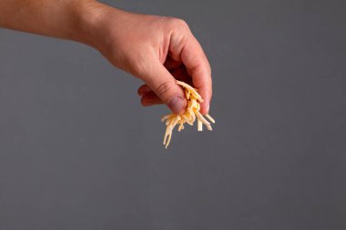 Closeup of man hand sprinkle grated cheese over dark background clipart