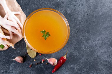 Koyu gri arka planda tavuk kemiği çorbası ve arka planda sebzeler. Uzayı kopyala Üst Manzara. Metin için boşluk.