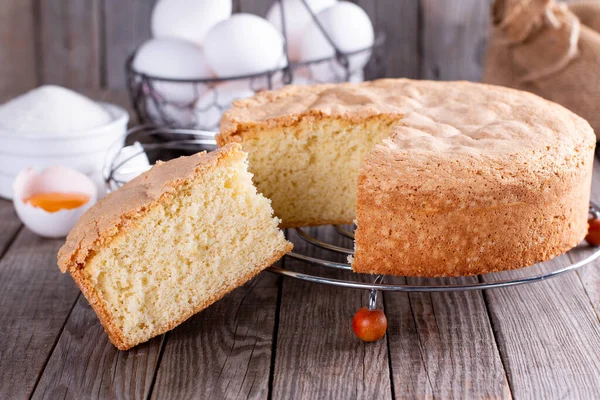 Homemade round sponge cake or chiffon cake on the grate so soft and delicious with ingredients: eggs, flour on wood table. Homemade bakery concept for background and wallpaper.