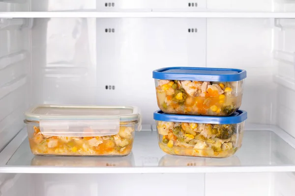 Frozen food in a container in the freezer. Refrigerator with frozen food. Ready meal