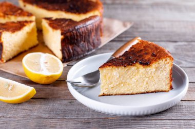 Bir parça San Sebastian Bask peyniri tabakta, ahşap bir masa üzerinde limon ve bir fincan çay.