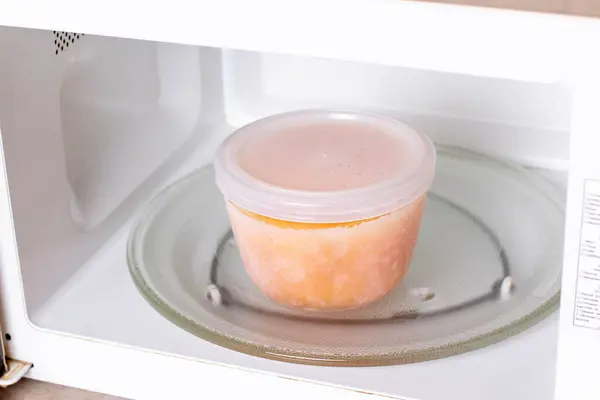 Frozen pumpkin soup in the microwave. Frozen food. Frozen soup. Preparing food for the week — Stock Image Frozen Pumpkin Soup Microwave Frozen Food Frozen Soup Preparing Food Stock Photo