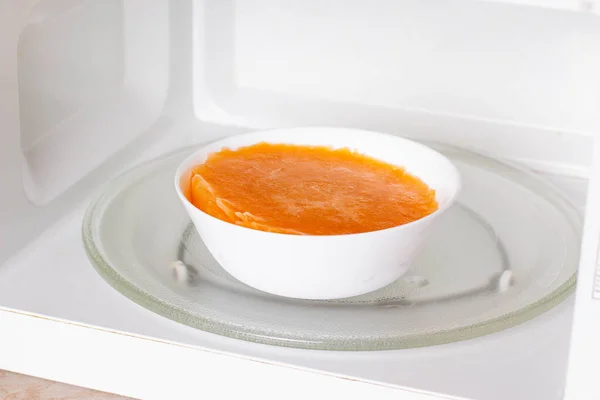 Frozen pumpkin soup in the microwave. Frozen food. Frozen soup. Preparing food for the week — Stock Image Frozen Pumpkin Soup Microwave Frozen Food Frozen Soup Preparing Food Stock Photo