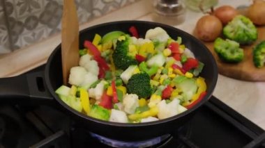 Cooking of frozen vegetables in frying pan. Frozen vegetables frying on hot pan. Natural food ingredients for healthy eating. Semi-finished food.