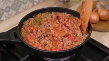 Bolonez sosu ve kıyma tavada ahşap bir spatulayla karıştırılır. İtalyan yemeği konsepti. Ev mutfağı.