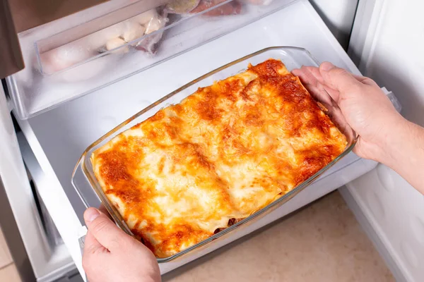 Frozen ready meals. Man\'s hands are taking frozen lasagna from the freezer of the fridge. Concept of ready made frozen dishes and saving time on cooking food.