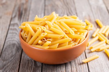 Tahta masadaki kasede çiğ makarna.