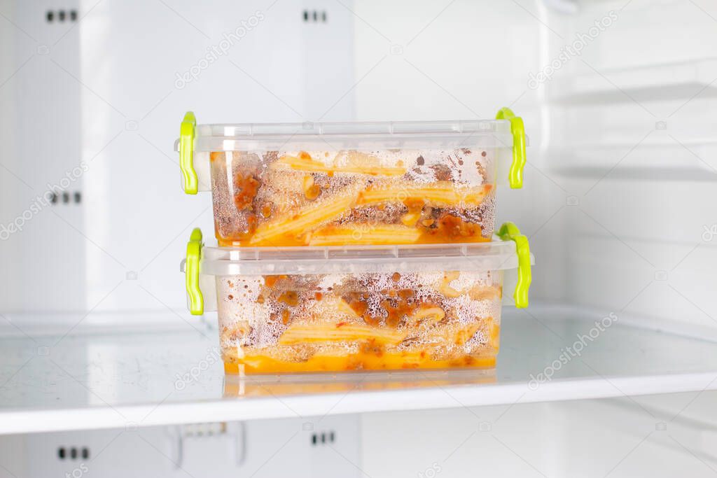 Ready frozen meal in a container in the refrigerator. Frozen food in the freezer. Fast cooking concept