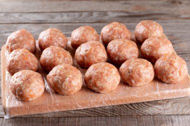 Tahtadaki çiğ, yarı bitmiş donmuş köftelere yakından bak. Pirinç, soğan ve etle birlikte.