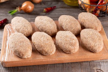 Donmuş pirzolalar tahta bir tahtanın üzerinde duruyor. Çiğ et yarı pişmiş ürünler pişirmeye hazır.