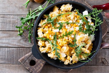 Çırpılmış yumurta, mısır, peynir, otlar ve sebzeler ahşap bir masada, üst manzara. Nefis ev yapımı kahvaltı.