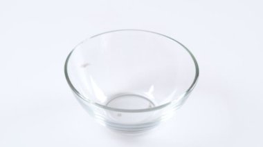 Beyaz arka planda cam bir kasede yeşil mercimek. Sağlıklı organik gıda diyeti kavramı. Taze doğal besin maddesi, yavaş çekim.