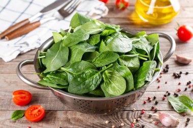 Taze taze ıspanak yaprakları ahşap bir masada süzgeçte.