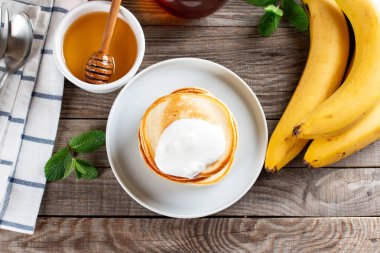 Krepler. Ekşi kremalı krep yığını. Tahta bir masada lezzetli kahvaltı yemekleri. Üst görünüm