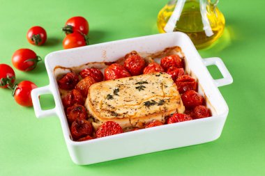 Renkli bir arka planda, güveç kabında domates, peynir, sarımsak ve ottan yapılan popüler viral Feta makarna tarifi. Fetapasta.