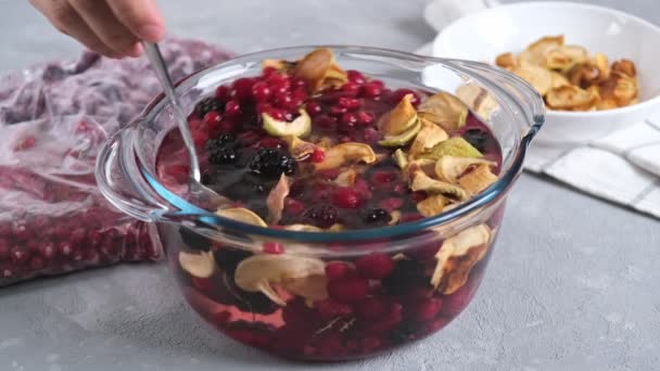用烘干的苹果和冰冻的浆果在清淡的背景下烹调自制的健康饮料或堆肥 — 图库视频影像